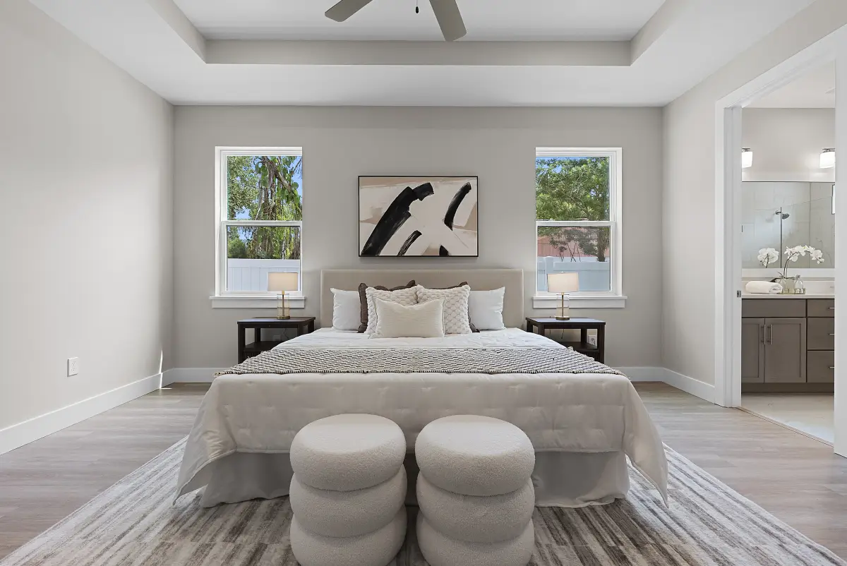 Guest bedroom with a tray ceiling, abstract art, and round ottomans