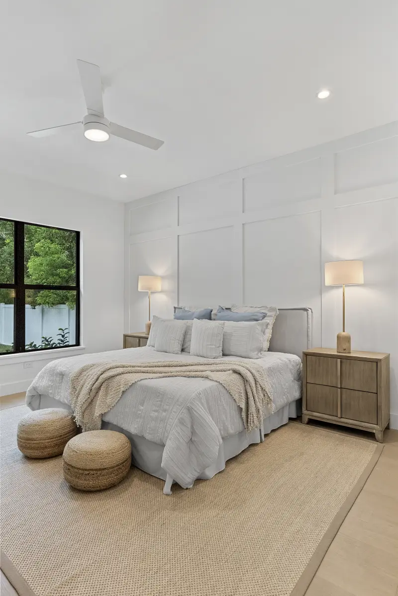 Primary bedroom with an accent wall and floor-to-ceiling black windows
