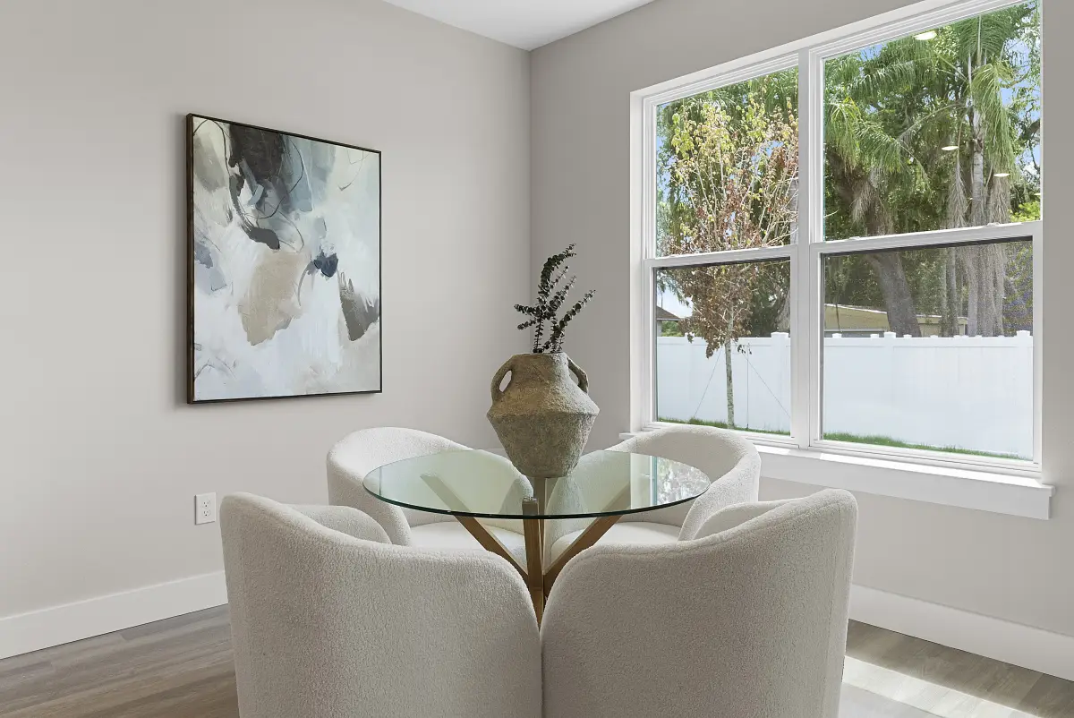 Breakfast nook with a round glass table, boucle chairs, and abstract art
