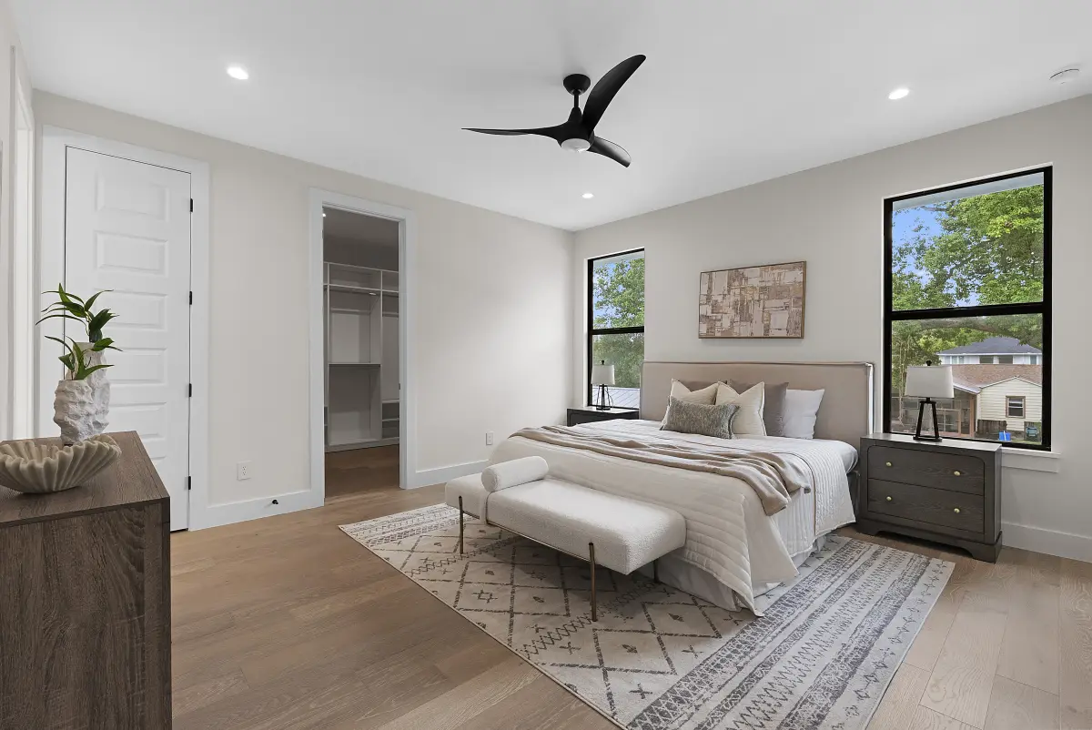 Staged primary bedroom with a tray ceiling and neutral bedding